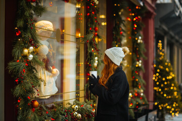 Woman admiring holiday window display in winter in Quebec, Canada