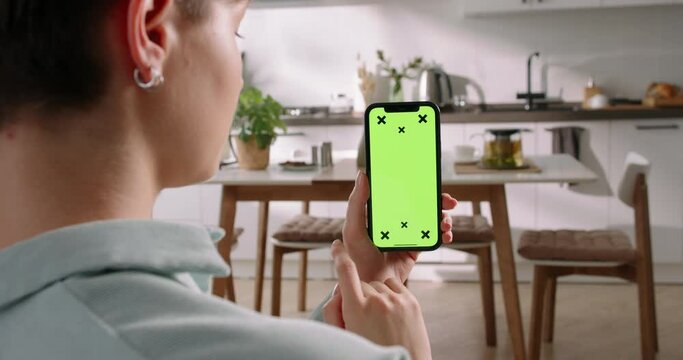 Woman grips smartphone with green screen tracking points. Scrolling feed and tap at bottom, online shopping, placing orders, making secure payments, add to cart, making choice, launch of smart home