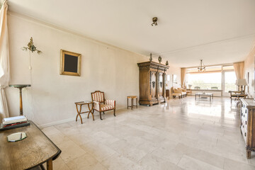 a living room with white tile flooring and large windows looking out onto the terraced garden area in the background
