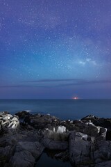 Vertical shot of the rocky coast under the scenic starry sky at night