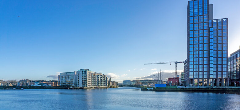 the view from the North Wall Quay of the River Liffey in Dublin, Ireland, with the Capital Building on the right, and the village of Ringsend on the left. In the distance the Aviva stadium.