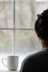 unrecognizable woman in front of window in winter