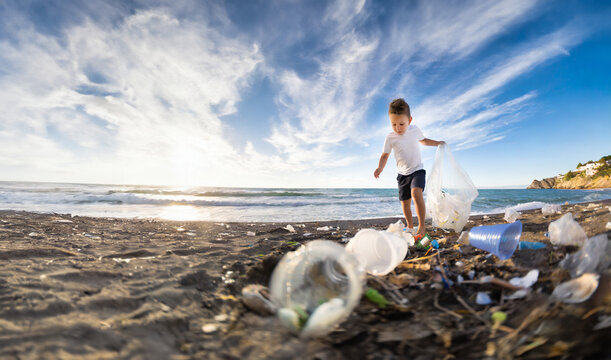 Child cleans the beach from plastic waste left by the sea