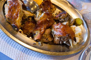 Chopped grilled chicken served on metal dish with orange slice..