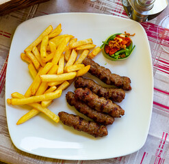 Delicious Balkan dish Cevapcici, grilled minced meat garnished with fries and sauce