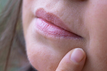 close up lips of mature female face, woman 50 years old carefully examines wrinkles around mouth,...