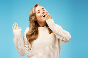 Portrait beautiful woman with silky, wavy hair yawning with closed eyes isolated on blue background