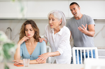 Obraz premium Family of three - mother-in-law, daughter and son quarreling in kitchen