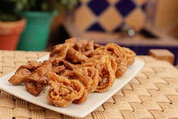 Moroccan chebakias on a white plate in a patio with plants
