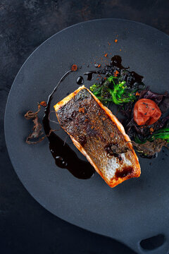 Traditional Japanese gourmet salmon fish steak tataki with algae, umeboshi fruit and wakame served as top view on a design plate with copy space