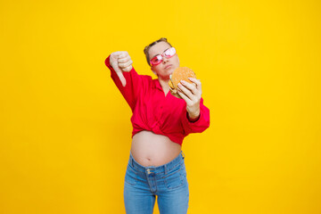 A cute pregnant woman in a pink shirt and pink glasses eats fast food. A pregnant woman on a yellow...