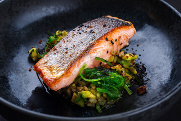 Traditional Japanese gourmet salmon fish steak tataki with chopped avocado, rice and wakame served as close-up on a design bowl