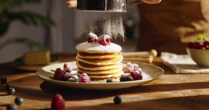 American traditional breakfast on kitchen background. Unknown sprinkles powdered sugar on pancake pancakes with berries. Advertising. Little celebration of taste for weekend morning. Gluten-free