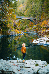 Moulton Falls Regional Park, Yacolt, Washington, USA. Girl standing and looking at Moulton Falls Bridge over the East Fork Lewis River.
