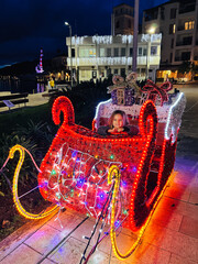 Little girl sits in Santa sleigh glowing with lights