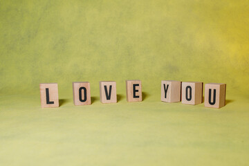 word LOVE YOU constructed by wooden letters on yellow background with copy space to give a message advertising concept