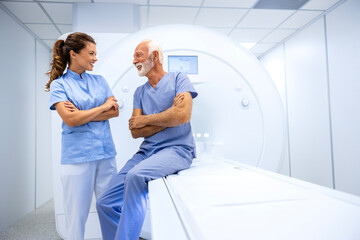 Female doctor preparing and encouraging senior man before MRI scan or CT procedure in hospital.