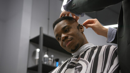 Barber cuts hair using dangerous razor. Creating complex hairstyle in barbershop