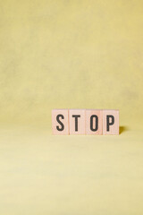 STOP word constructed by wooden letters on yellow background with copy space to give a message...