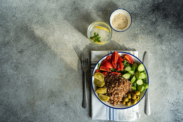 Healthy lunch bowl with glass of water with lemon on gray table