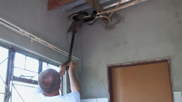 man with a shovel trying to catch and safely remove and relocate african rock python hiding in the corner of the room at a farm in Botswana