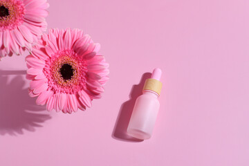 Pink serum oil face care bottle with flower gerberaand stone, mockup container