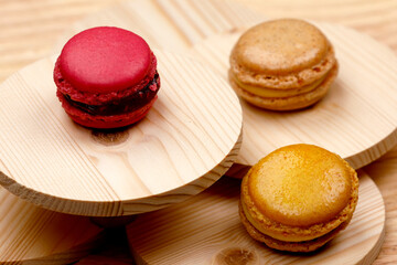 Macarons ai frutti di bosco ,alla crema e alla nocciola su sfondo di legno