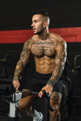 Fototapeta na wymiar Chico joven tatuado y musculoso posando con iluminación de estudio en gimnasio de crossfit