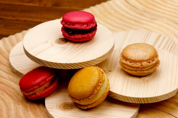Macarons ai frutti di bosco,alla nocciola ,alla crema e alla fragola su sfondo di legno