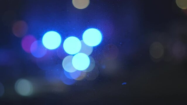 Blurry lights from fire truck shining on street outside of window alerting people about emergency. Flashing blue and red warning lights. Bokeh effect