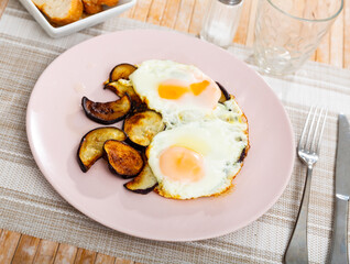 Image of a appetizing fried eggs, cooked with sliced roasted eggplant
