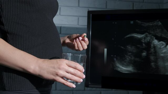Lady drink pregnant vitamins. A view of female drink pregnant vitamins for her future baby health indoor.