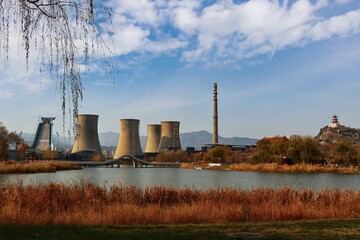 Fototapeta na wymiar Old steel factory view with a chimney and cooling tower with lake near