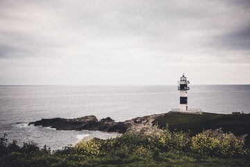 Fototapeta na wymiar Gray cloudy sky over the sea with a lighthouse on the coast