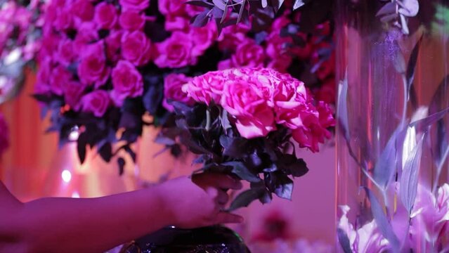 woman's hands arranging rose flowers in vase to decorate event