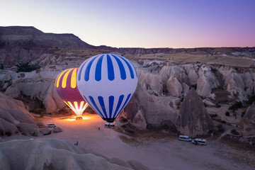 two hot air balloons full of tourists, about to take off at dawn between fairy chimneys, service...