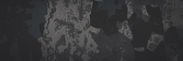 Dark wide panoramic background. Peeling paint on a concrete wall. Faded dark texture of old cracked flaking paint. Weathered rough painted surface with patterns of cracks. Shaded background for design