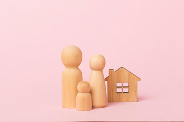 Wooden family figures with house on color background
