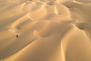 Fototapeta na wymiar Beautiful view of a person walking on dunes during sunrise