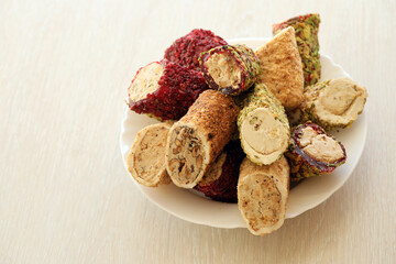 Many rolls of turkish delight with different flavors and fillings in white plate on table. Cuts of...