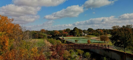 Fototapeta na wymiar Drone shot of a metallic bridge connecting two parts of a green park