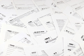 Many tax form blanks lies on table close up. Tax payers paperwork routine and bureaucracy concept....