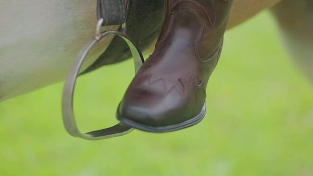 Close-up of the foot with leather boot in the horse's stirrup