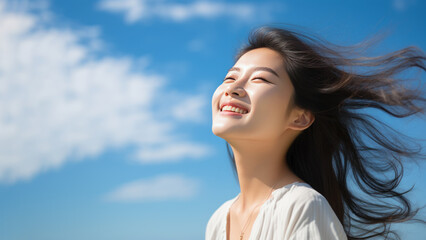 A Asian woman breathes calmly looking up isolated on clear blue sky