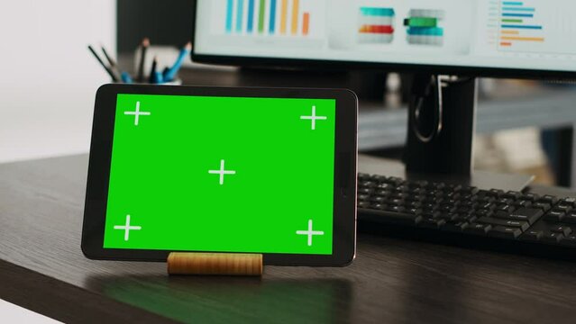 Greenscreen projection on interactive tablet with chromakey theme appears on company desk. Isolated mockup design displayed on advanced handheld gadget, blank copyspace layout. Close up.