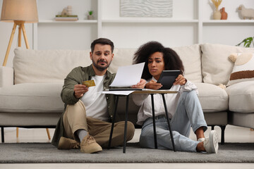 Confused couple with calculator, credit card and debt notification planning budget at home. Financial problem