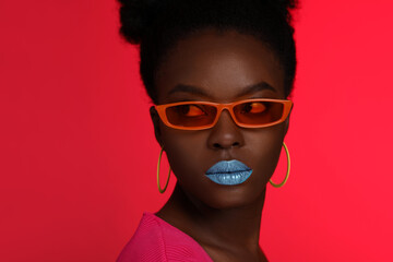 Fashionable portrait of beautiful woman with stylish sunglasses on coral background