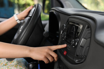 Naklejka premium Choosing favorite radio. Woman pressing button on vehicle audio in car, closeup