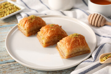 Delicious sweet baklava with pistachios on light blue wooden table, closeup