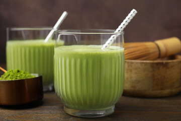 Glass of tasty matcha smoothie with straw on wooden table, closeup